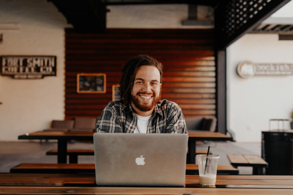 Hip smiling guy on laptop at urban coffee shop